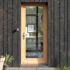 a wooden building with a door and potted plants