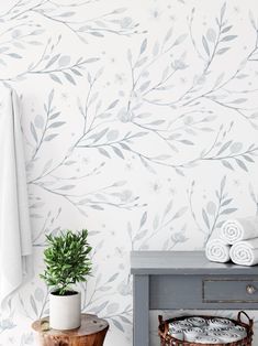 a bathroom with a plant and towels on the shelf in front of it, next to a gray cabinet