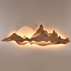 a wooden wall light with mountains on the side and a sun in the sky behind it