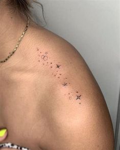 the back of a woman's shoulder with stars and moon tattoos on it