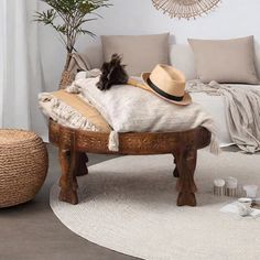 a cat laying on top of a wooden bench next to a white couch and rug