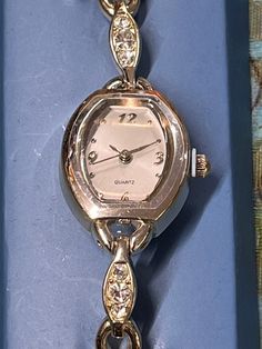 "Watch, Women's Gold Tone Watch Tennis Bracelet Design Japan Movement Quartz   The face has gold numerals land encircled with silver which is encircled by gold tone.  gold tone link bracelet. New old stock. never worn.   Measurements 7 1/4\" length.   Face is approximately 1\" x 3/4\".  The back is stainless steel with a Japan movement.  Will need a new battery.   Perfect for a gift or just to treat yourself.    VERY IMPORTANT  Please make sure to double check with me about verifying your shipping costs before you pass on this item due to high shipping costs. Send me your postal or zip code and I will get you an accurate quote.  It may be much lower than what you've been quoted by ETSY. #GRCd" Elegant Nickel-free Metal Watches, Adjustable Analog Jewelry For Formal Occasions, Metal Jewelry And Watches With Round Dial For Anniversary, Elegant Nickel-free Watches As Gifts, Silver Watch As A Gift, Formal Analog Metal Watch, Silver Watches Suitable For Gifts, Tennis Design, Design Japonais