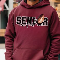 Introducing the ultimate Senior Class of 2024 custom name and number football hoodie, where style meets spirit!  🏈🎓 Picture your graduate stepping onto the field, their name and number proudly displayed on this exceptional hoodie. It's not just an outfit; it's a living testament to their dedication and the unforgettable journey they've embarked on. 💫 This hoodie is more than apparel; it's a symbol of your Senior's athletic prowess and an embodiment of their commitment to excellence. It's a tangible reminder of the victories they've achieved and the victories yet to come. 🌠 As a parent, you've watched your child's passion for the game grow from the very first kick to this triumphant moment. This hoodie encapsulates their achievements and the unwavering support that has been the driving Pre-shrunk School Spirit Hoodie For Sports Season, Collegiate Style Hoodie For Game Day, Sports Season, Football Season Sports Fan Hoodie, Collegiate Hoodie For Sports Events And Sports Season, Collegiate Style Hoodie For Sports Events, Hooded Hoodie For Football Season Streetwear, Team Spirit Hoodie For College Sports Season, Team-colored Football Season Sports Hoodie, Team Spirit Hoodie For College Sports