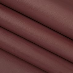 a close up shot of the maroon leather textured material for a chair cushion or ottoman