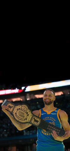 a man holding a basketball shoe in his right hand and smiling at the camera while standing on a court