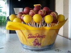 a bowl filled with cake pops covered in yellow and red frosted icing on top of a counter