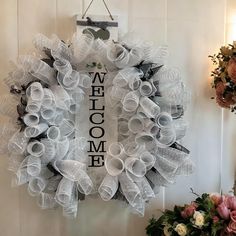 a welcome wreath hanging on the wall next to some flowers and other decorating items