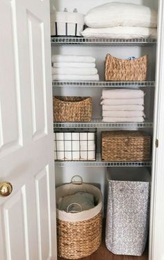 an organized closet with baskets and towels