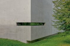 a concrete building with two windows in the grass