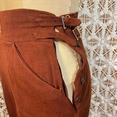 "These are rust-colored wool riding trousers with a high waist. They fasten with a button fly & 2 buckles at the side.  Full in the hip & tapered leg. Creases are ironed in.  Stirrups fasten with buttons. Black & red acetate waistband & pocket linings. 2 side pockets.   Designer: G&B Color: Rust Material:  wool Condition: Pre-owned in very good condition.  One of the seat pockets is missing its button Size: fits modern XS with up to a 24\" waist MEASUREMENTS (inches)  Waist flat across the front Riding Trousers, Riding Pants, Vintage Clutch, Floral Swimsuit, Leather Detail, Wool Trousers, Stirrups, Natural Cleaning Products, Philadelphia Pa