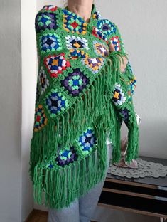 a woman wearing a green crocheted shawl with flowers and leaves on it