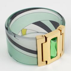 Lovely chunky Emilio Pucci gilded metal, acrylic, and silk bracelet bangle. Large bangle shape of a clear acrylic band with multicolor Pucci silk inclusion. The bracelet is also ornate with a gilt metal faux hinge topped with a huge rectangular faceted resin rhinestone. Assorted colors of emerald green, avocado green, black, and white. Emilio Pucci's hallmark is engraved on the inside and reads "Emilio Pucci - Made in Italy". Comes with its original branded gift box. Measurements: inside across Designer Green Bracelets As Gift, Designer Green Bracelets For Gifts, Modern Lucite Bangle Jewelry, Lucite Bangle Bracelet As Gift, Lucite Bangle Bracelet For Gift, Lucite Bangle Bracelets As Gift, Modern Lucite Bracelets As A Gift, Elegant Green Bracelets, Green Avocado