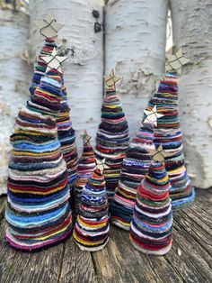 three small trees made out of yarn sitting on top of a wooden table