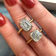 two engagement rings on top of each other in front of a woman's hand