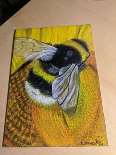 a drawing of a bee on top of a yellow piece of paper with black and white wings