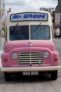 an old pink and white truck parked on the street