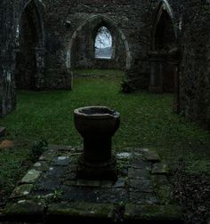 an old stone building with green grass in the foreground