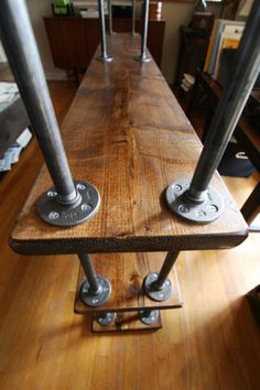 a long wooden table with metal pipes on it's legs and some wood flooring