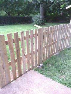 a wooden fence is in the grass next to a yard with a baseball bat on it