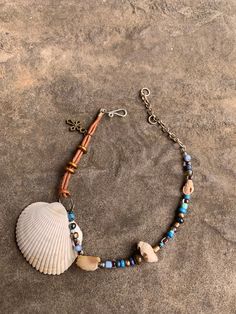 Cockle and drill shell ankle bracelet. Glass and brass beads. Bronze cross charm. 9 1/2" expandable to 11 1/2" double stranded leather ankle bracelet. Hand crafted silver plated hook and ring closure. Adjustable Wire Wrapped Beaded Bracelets For Beach, Beaded Waxed Cord Bracelet, Adjustable Beaded Bracelet With Lobster Clasp For Festival, Adjustable Metal Jewelry For Beach, Adjustable Wire Wrapped Bracelets For The Beach, Adjustable Shell Jewelry Nickel Free, Adjustable Beaded Bracelets With Charms For Beach, Adjustable Hand Wrapped Shell Jewelry, Adjustable Wire Wrapped Shell Jewelry