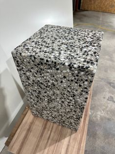 a black and white object sitting on top of a piece of wood next to a wall