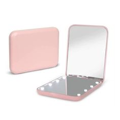 an open laptop computer sitting on top of a white table next to a pink mirror