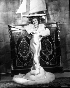 an old black and white photo of a woman in front of a bed with a sailboat on it