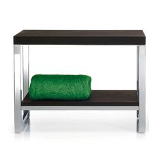 a green towel sitting on top of a wooden shelf next to a metal frame table