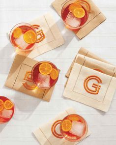 four glasses filled with orange slices on top of napkins