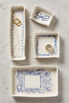 three small trays with wedding rings and ring holders in them on a white surface