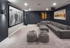 a large living room with grey couches and pictures on the wall