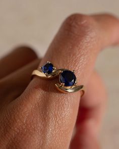 a woman's hand with a gold ring and two blue sapphires on it