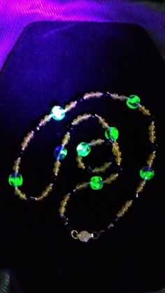 a black hat with green and white beads on it's side, next to a necklace