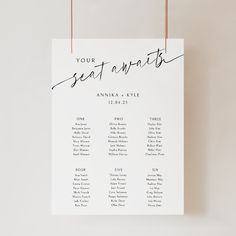 a seating chart hanging on a white wall with brown string attached to the back of it