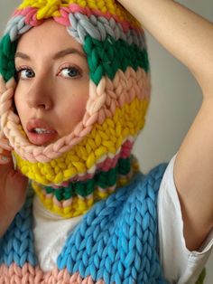 a woman wearing a multicolored knitted scarf covering her face