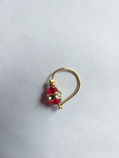 a pair of red and gold colored earrings on a white surface with one earring in the shape of a heart