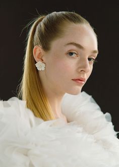 a woman with long blonde hair wearing a white dress and flower in her hair, looking off to the side