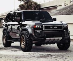 a black and silver suv parked in front of a building with palm trees behind it