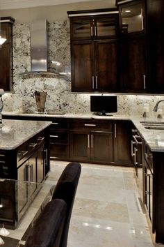 a kitchen with marble counter tops and dark wood cabinets