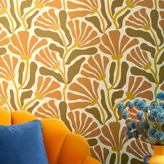 an orange and blue couch sitting next to a vase with flowers