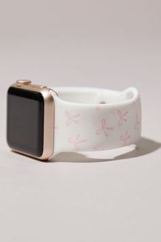 an apple watch with pink and white designs on it's wristband, against a gray background