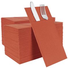 a stack of orange napkins with silverware on top of them, sitting next to each other