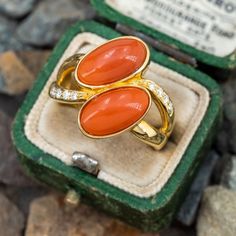 This gorgeous coral ring is centered with two (2), bezel set, oval cabochon cut natural coral. The ring features a split shank design and is accented with eight (8), bead set, round brilliant cut diamonds. The ring measures 18.1mm at the top, rises 5.7mm above the finger, tapering to 2.9mm wide and 1.3mm thick at the base of the shank. "K18 D0.11" is stamped on the inside shank. The ring is currently a size 6.5. Coral Ring, Natural Coral, Bead Set, Split Shank, Red Coral, Oval Cabochon, Round Brilliant Cut Diamond, Brilliant Cut Diamond, Bezel Setting