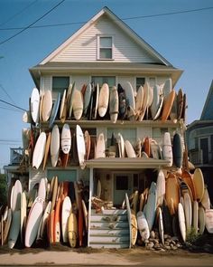 many surfboards are stacked on top of each other in front of a house