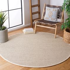 a living room with a chair, potted plants and a rug on the floor