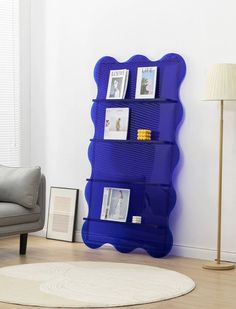 a living room with a gray chair and a blue shelf on the wall next to a lamp