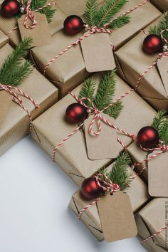 christmas presents wrapped in brown paper and tied with twine, pine needles and red ornament ornaments