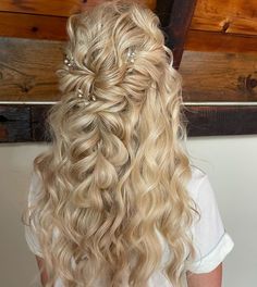 a woman with long blonde hair wearing a half up hairstyle and pearls in her hair