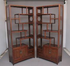 two wooden bookshelves sitting next to each other on top of a floor in front of a white wall