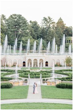 an engaged couple standing in front of a fountain